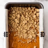 Streusel topping being added to pumpkin bread batter.