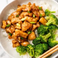 Bowl of rice with honey ginger chicken and broccoli on top.