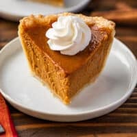 Slice of mini pumpkin pie with whipped cream on top.