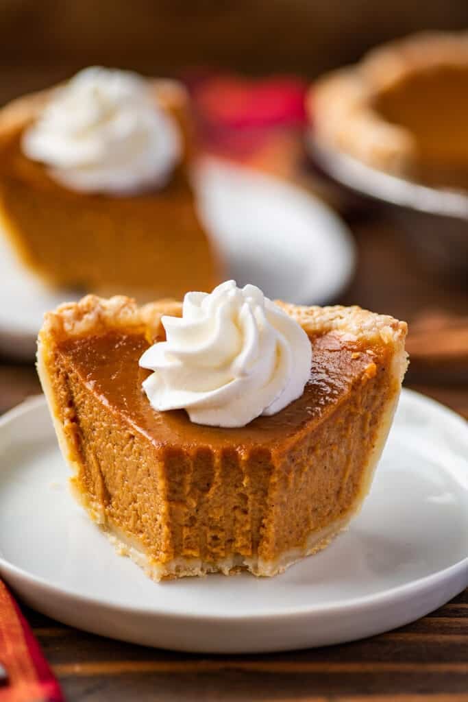 Small pumpkin pie slice with a bite taken out of it.