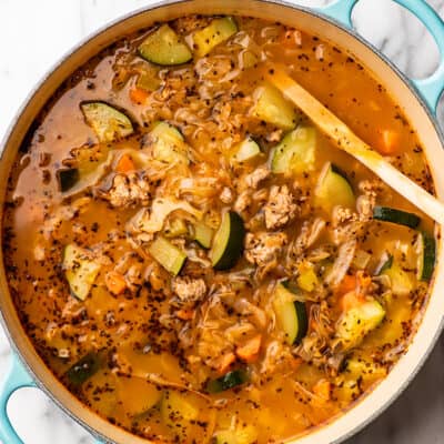 Ground turkey vegetable soup being stirred in a pot.