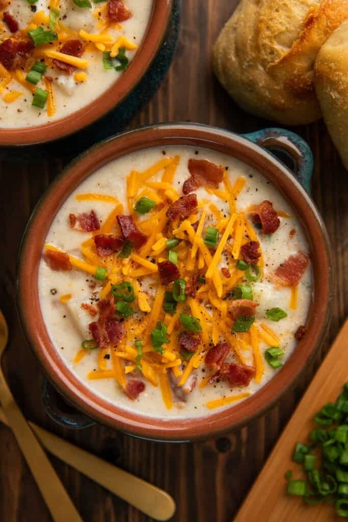Bowl of potato soup with bacon and cheese on top.