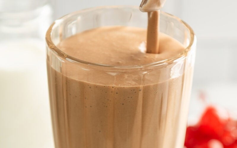 Chocolate malted milkshake being poured into a glass.