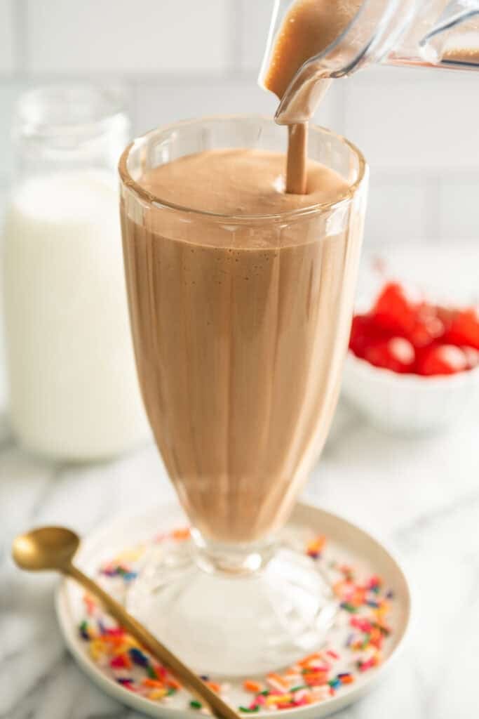 Chocolate malted milkshake being poured into a glass.