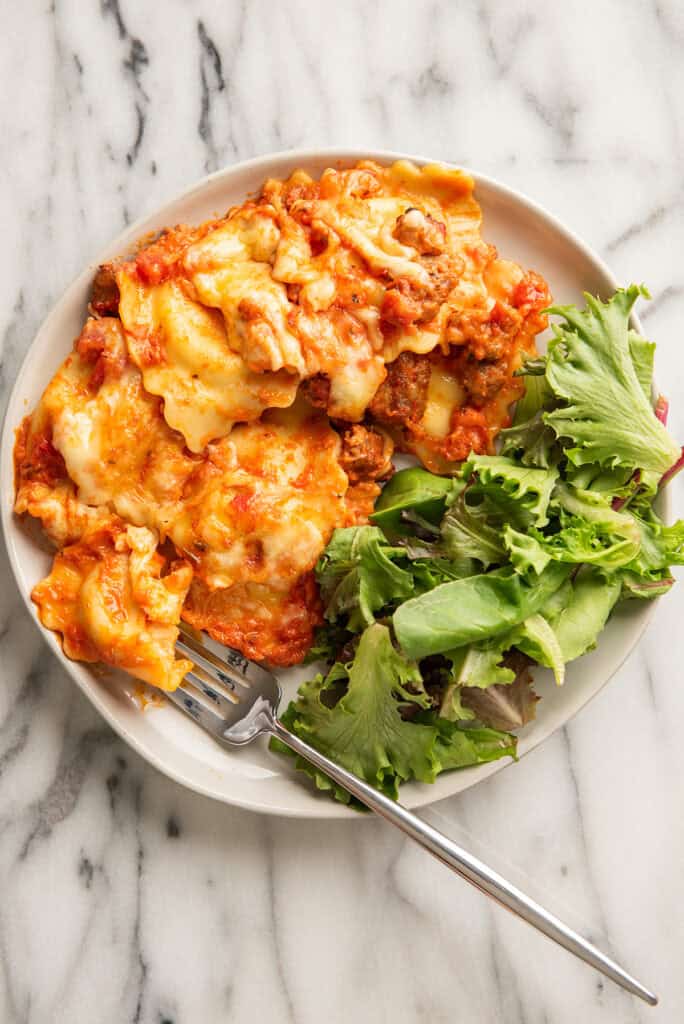 Baked ravioli on a plate with salad.