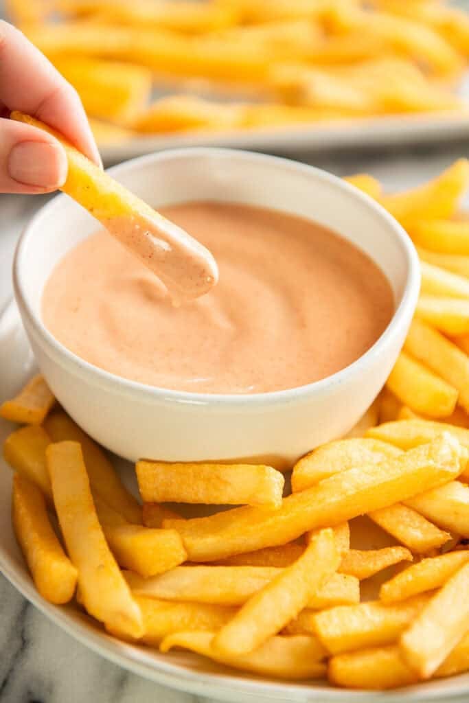 Fry being dipped into fry sauce.