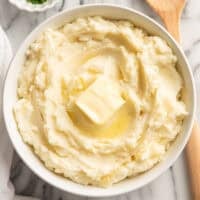 a bowl of sour cream mashed potatoes with a slice of butter on the top