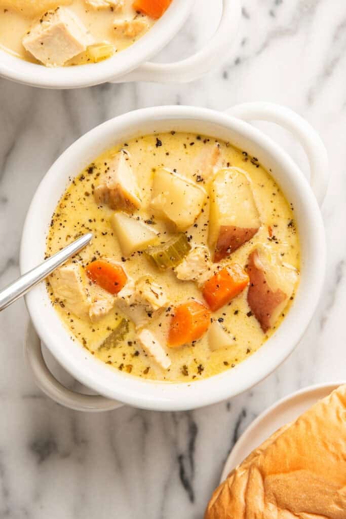 Creamy chicken and potato soup in a white bowl.