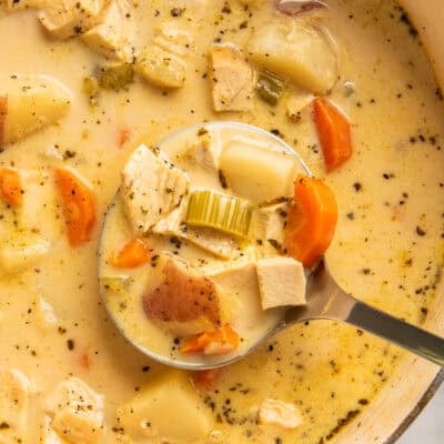 Close up of creamy chicken and potato soup being ladled out of a pot.